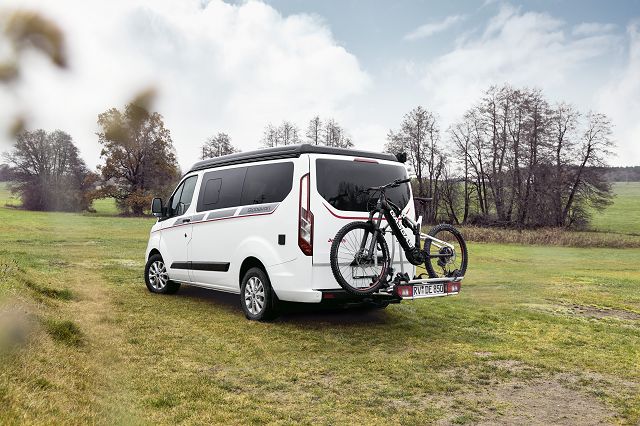 Globevan auf grüner Wiese mit montiertem Fahrradträger und Fahrrad darauf befestigt. 